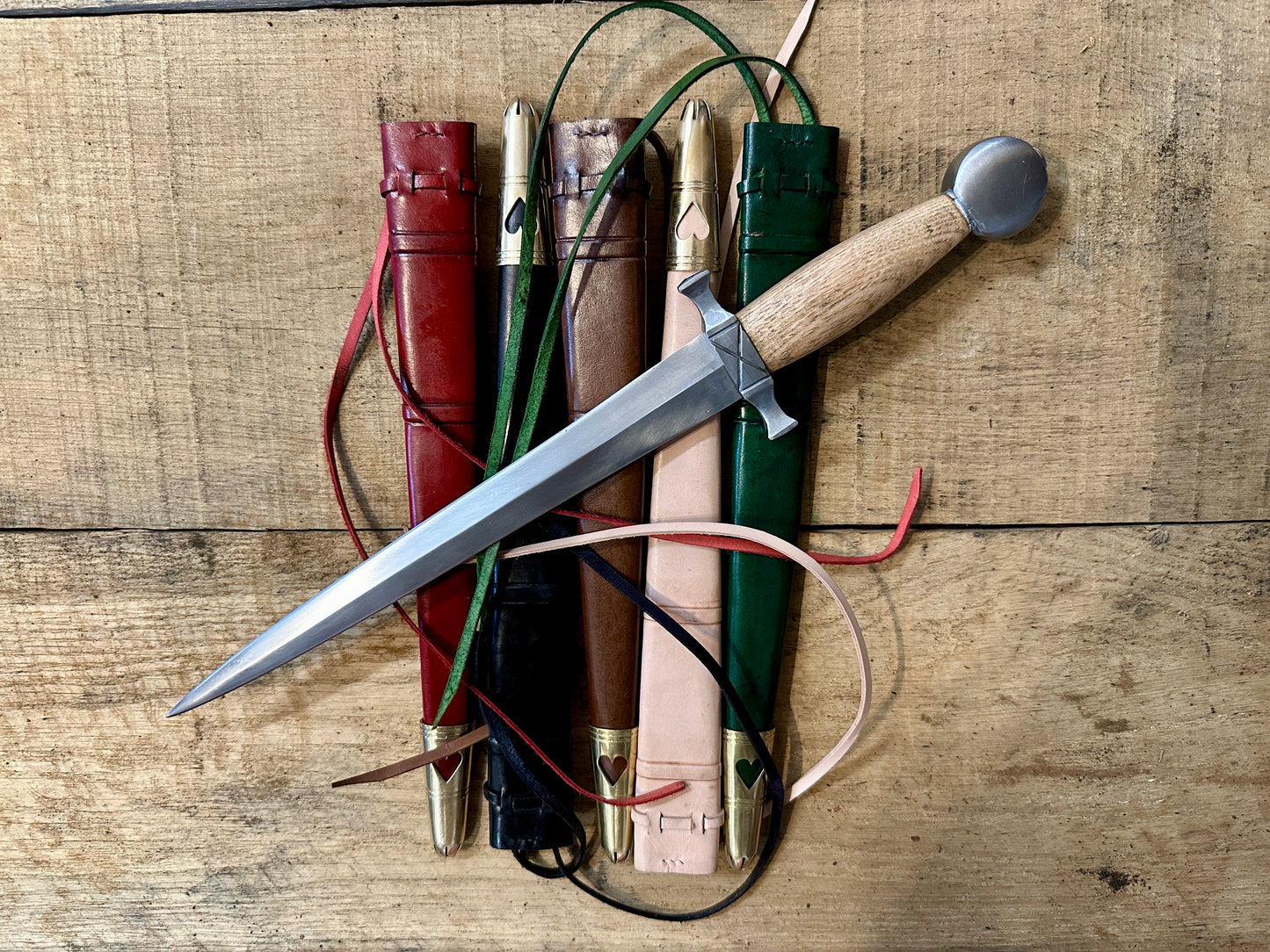 Tod Cutler 12thC Quillon Dagger lying on five scabbards in red, black, brown, natural and green