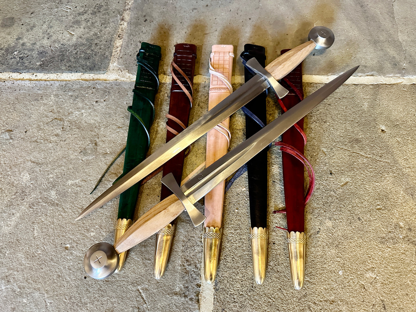 14thC Long Quillon Dagger - two opposing daggers on  green, red, natural, black and red scabbards