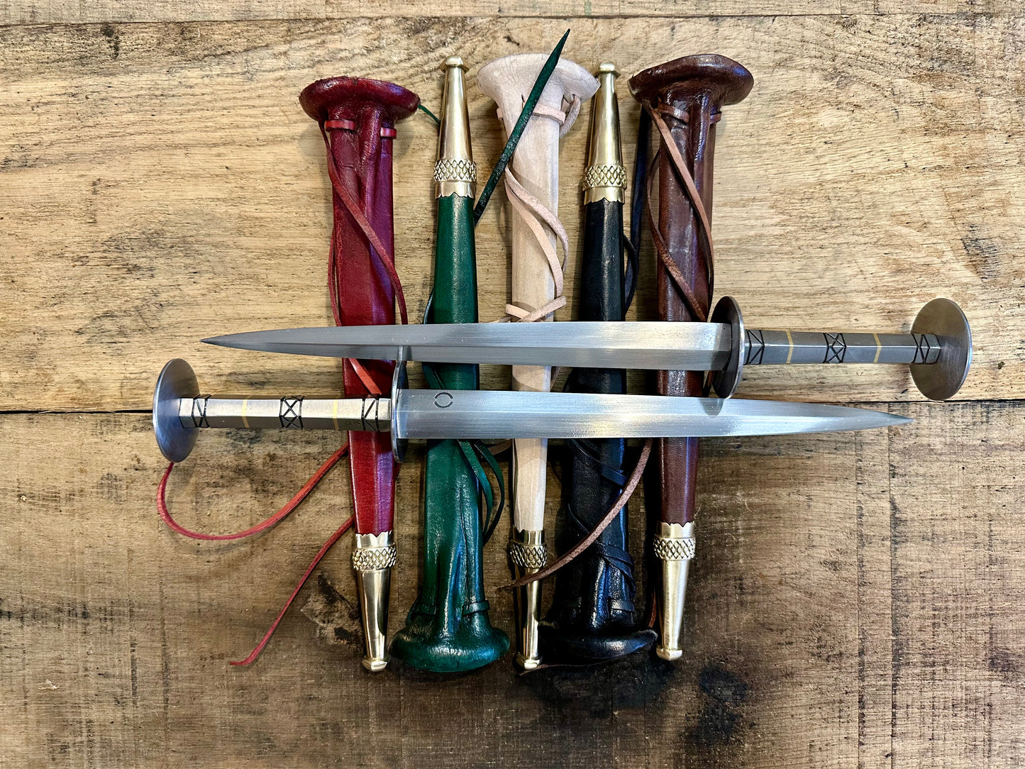 German Steel Rondel. Two lying on scabbards of red, green, natural, black, and brown