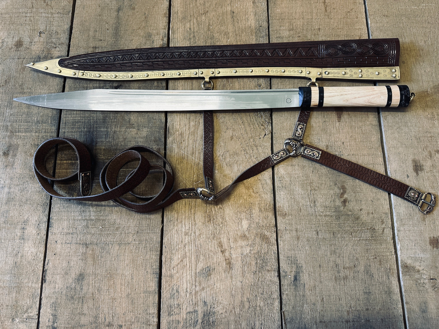 A sword Seax lying next to a brown scabbard.