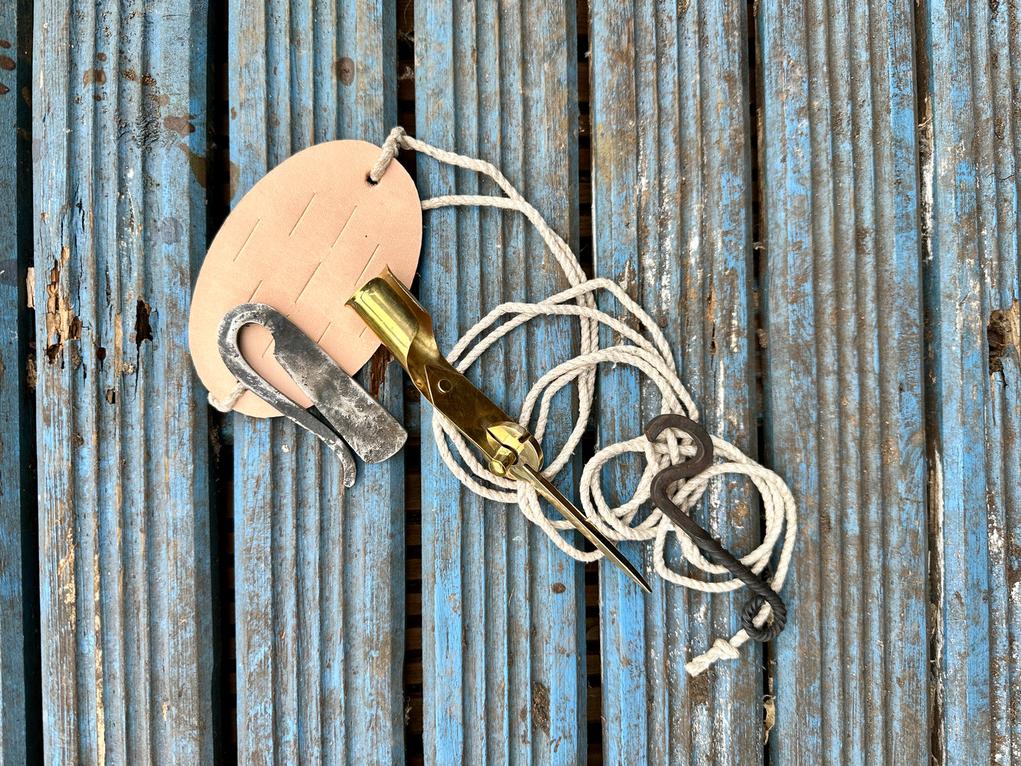 camping bundle containing a leather sling, a steel strike a light, bottle opener and brass folding candlestick