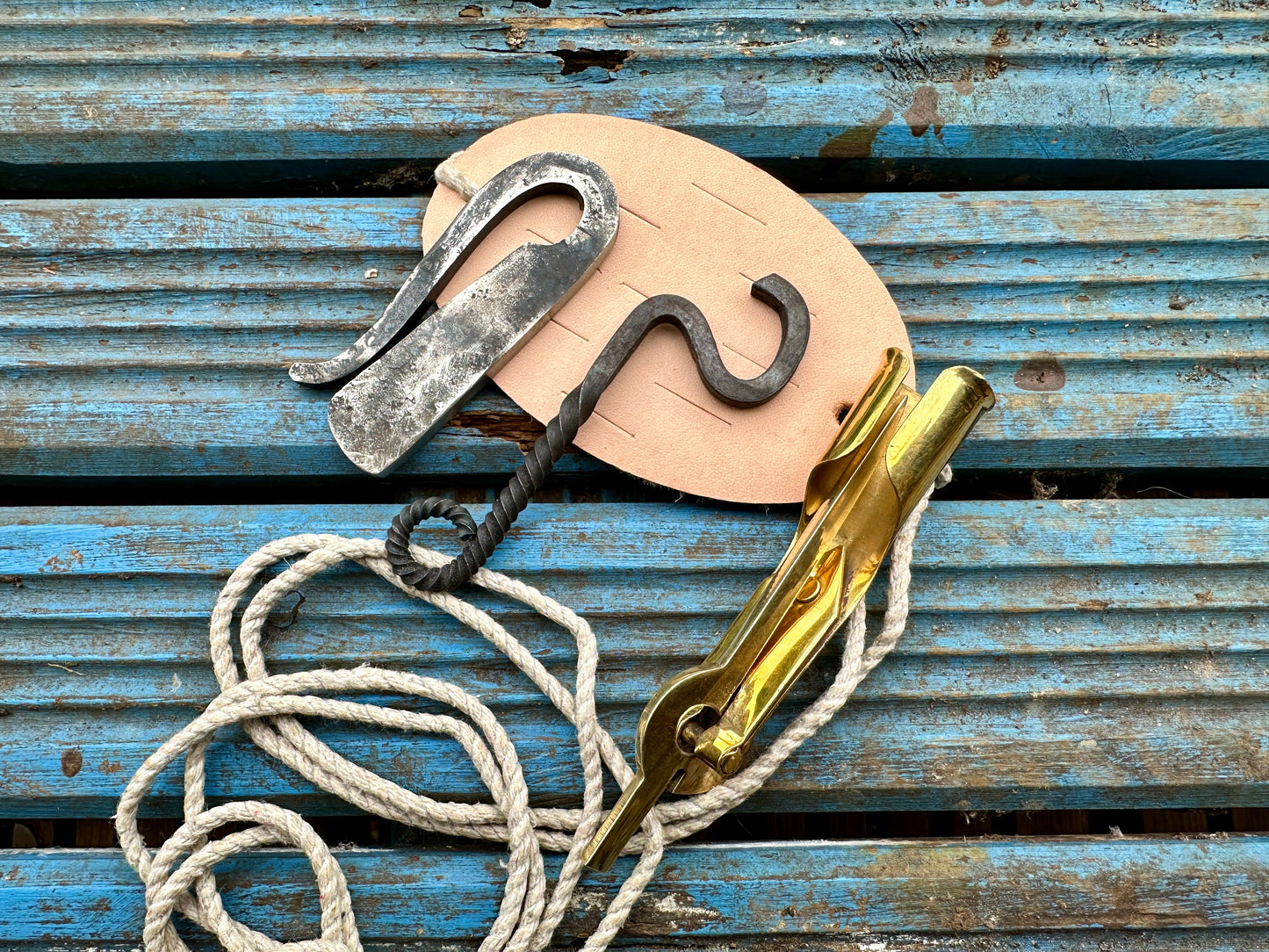 camping bundle containing a leather sling, a steel strike a light, bottle opener and brass folding candlestick