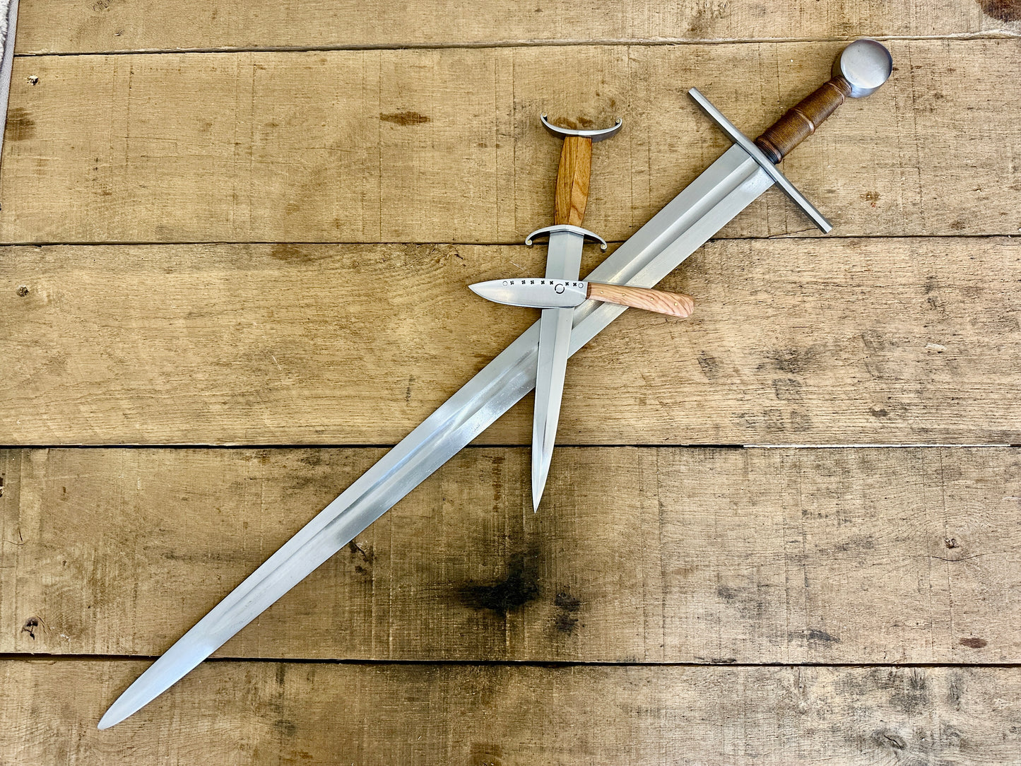 12th Century single-handed sword, 11-14th Century Antennae Dagger and 12-14th Century Peasants eating knife crossed (no scabbards)