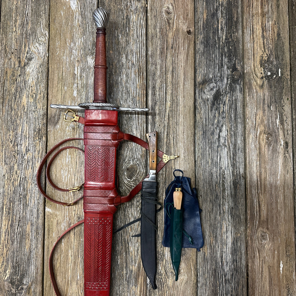 
                  
                    The Big Weapon Bundle. Sword, knife, eating set in sheathes and featuring a leather pouch. 
                  
                