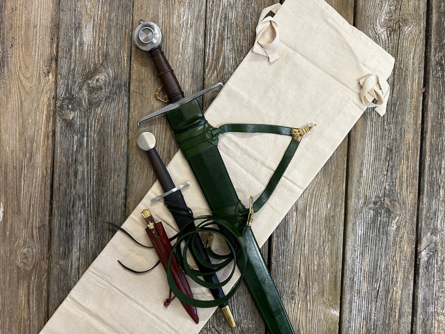 
                  
                    Castillon bundle with a sword and green scabbard, a quillon dagger with black scabbard and an eating set with knife and pricker and a red scabbard. There is also a free cotton sword bag.
                  
                