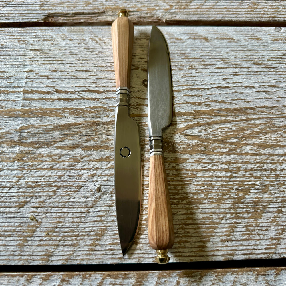 Two knives with wooden handles on a wooden surface