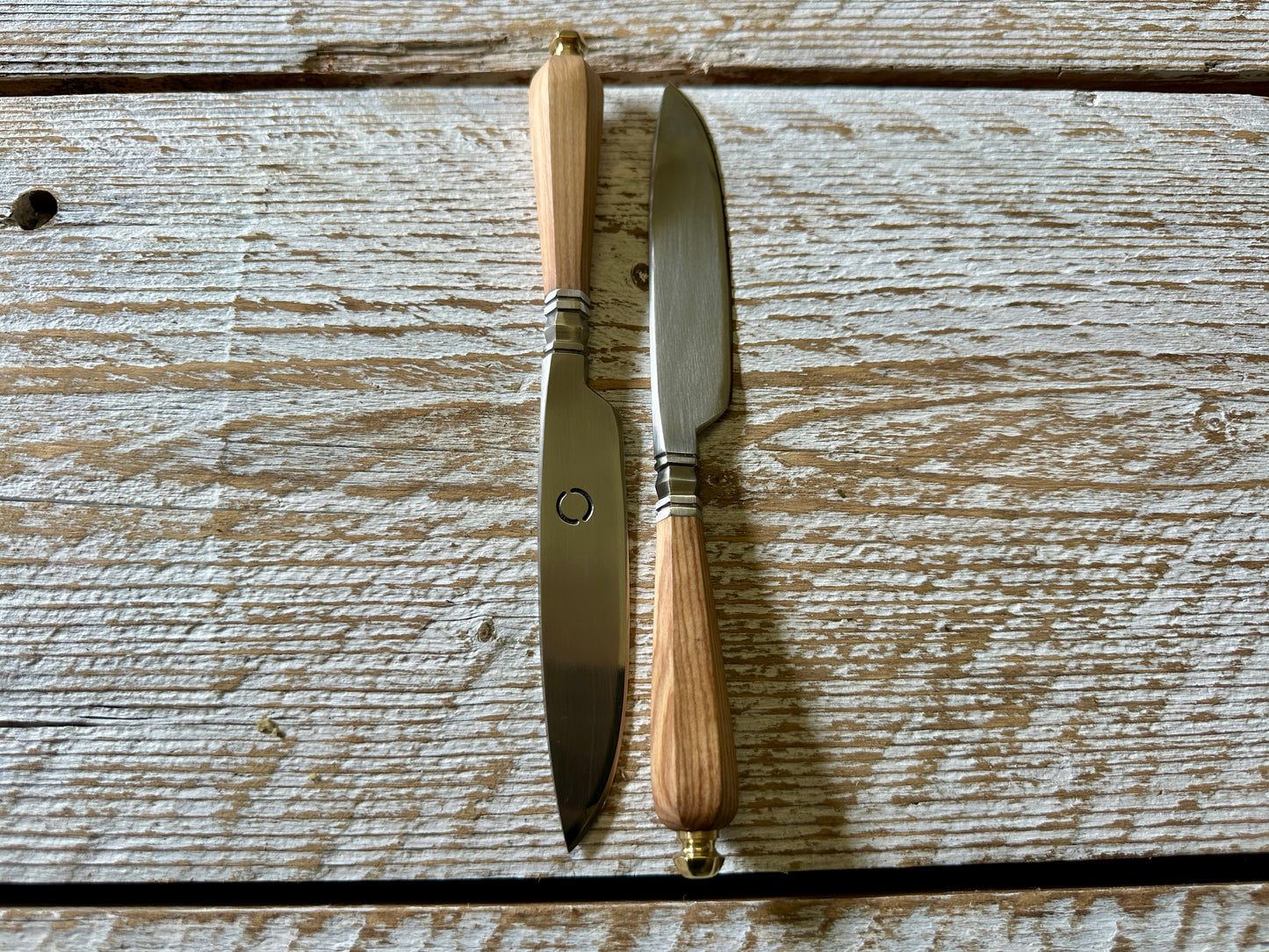 Two knives with wooden handles on a wooden surface