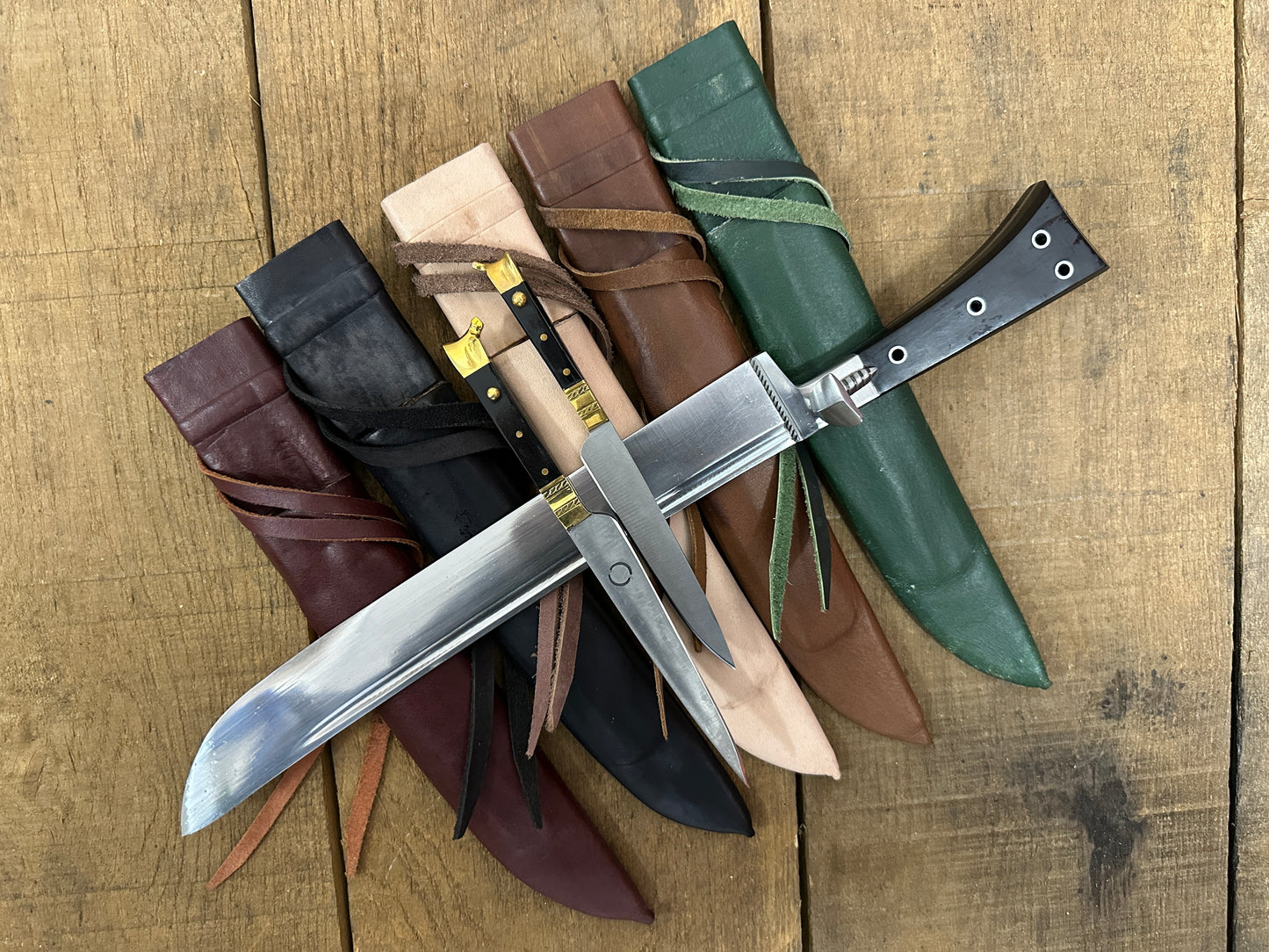 
                  
                    Bauernwehr with by knives resting on red, black, natural, brown and green scabbards
                  
                