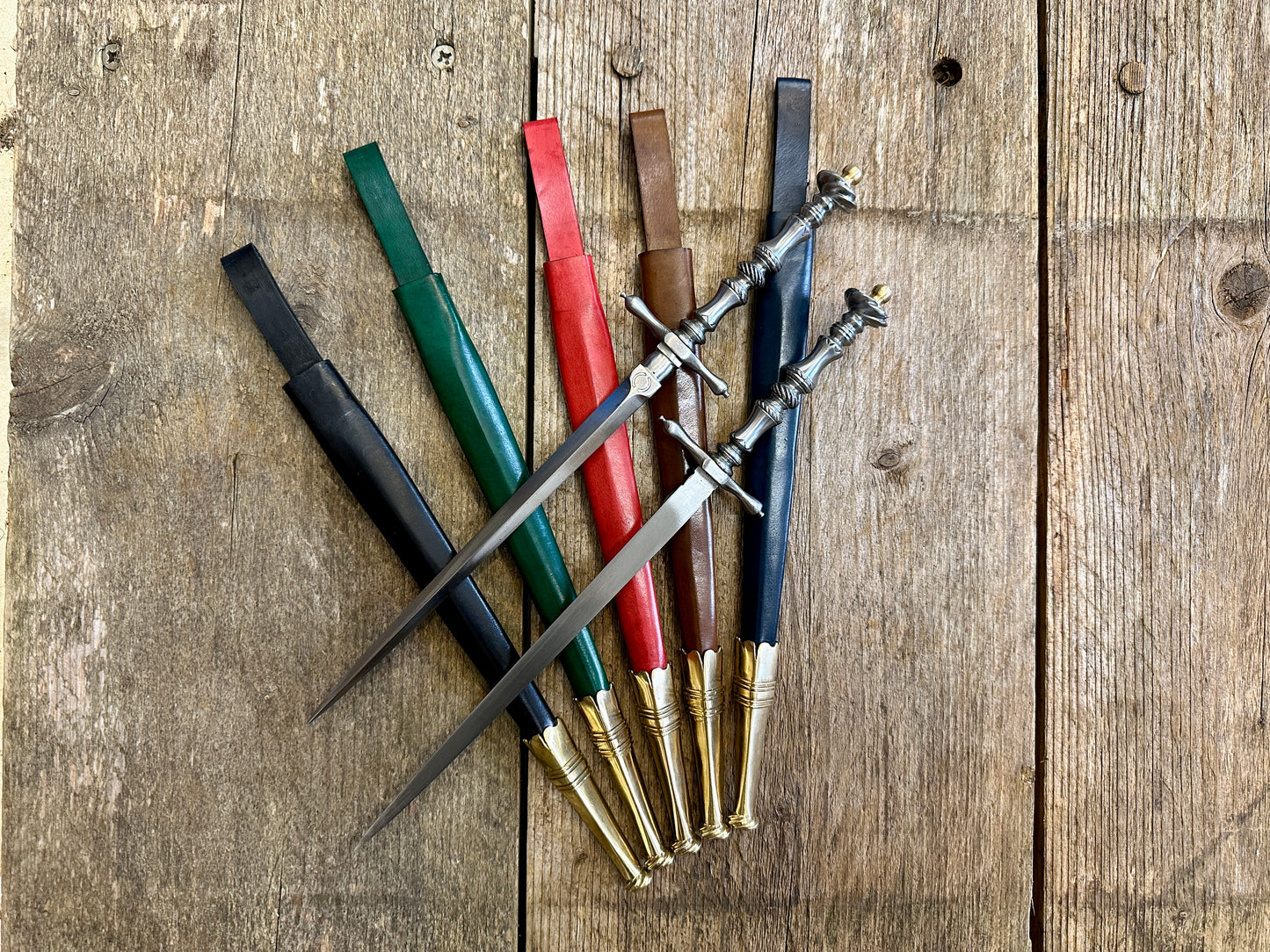 
                  
                    Two Pitt Rivers Stiletto daggers on blue, green, red, brown and black sheathes.
                  
                