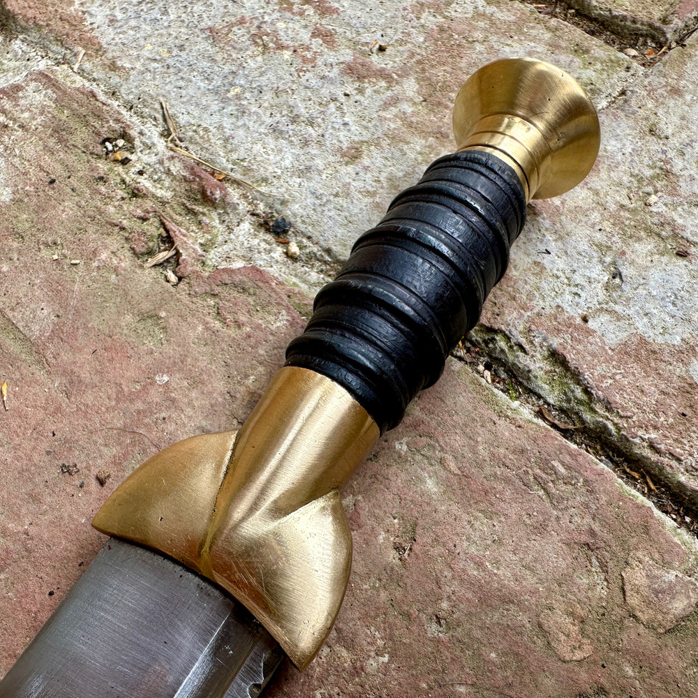 
                  
                    18thC Short brass and black wood dirk. Close up of grip.
                  
                