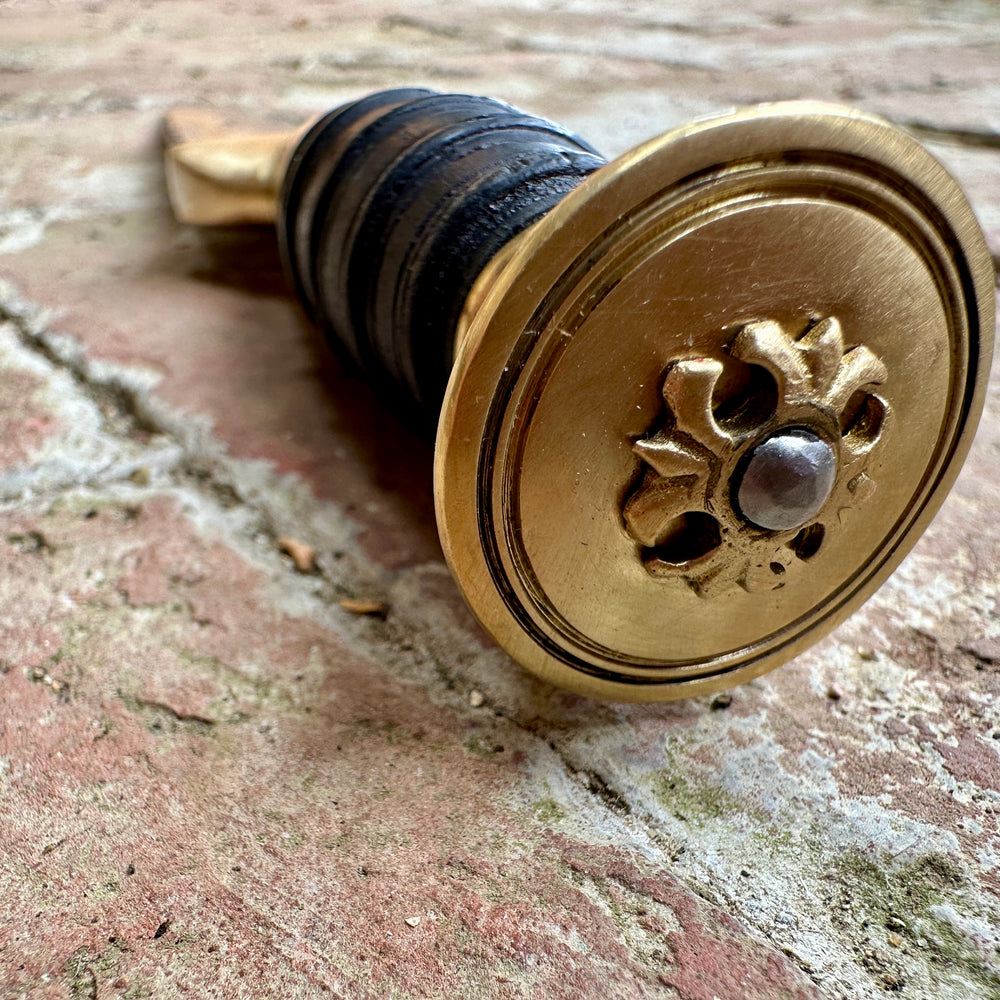 
                  
                    18thC short brass and black wood dirk. Close up of pommel. 
                  
                