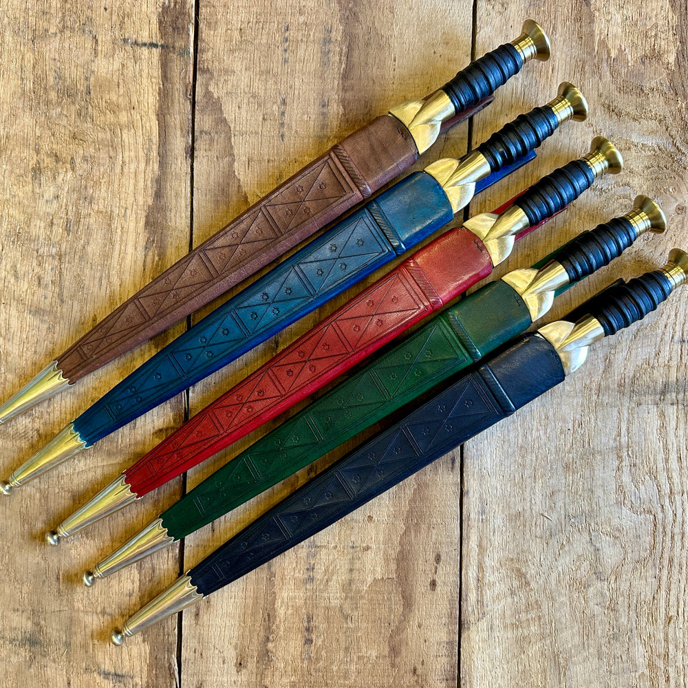 
                  
                    18thC long brass and wood dirk. Kives in all scabbards, red, brown, blue, green, black.
                  
                