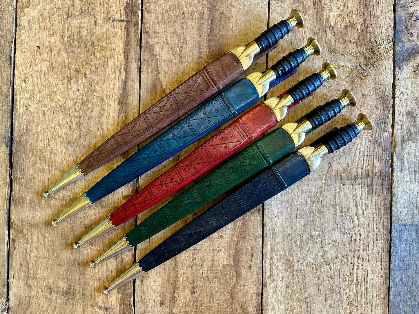 
                  
                    18thC long brass and wood dirk. Kives in all scabbards, red, brown, blue, green, black.
                  
                