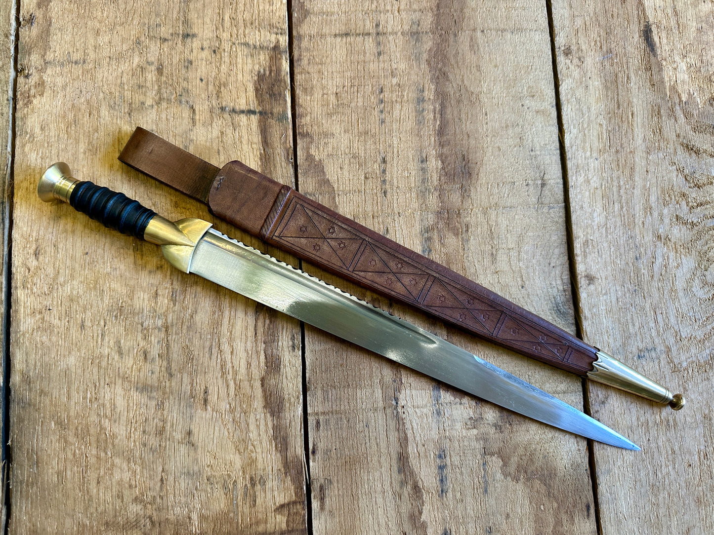 
                  
                    18thC long brass and wood dirk. With brown scabbard.
                  
                