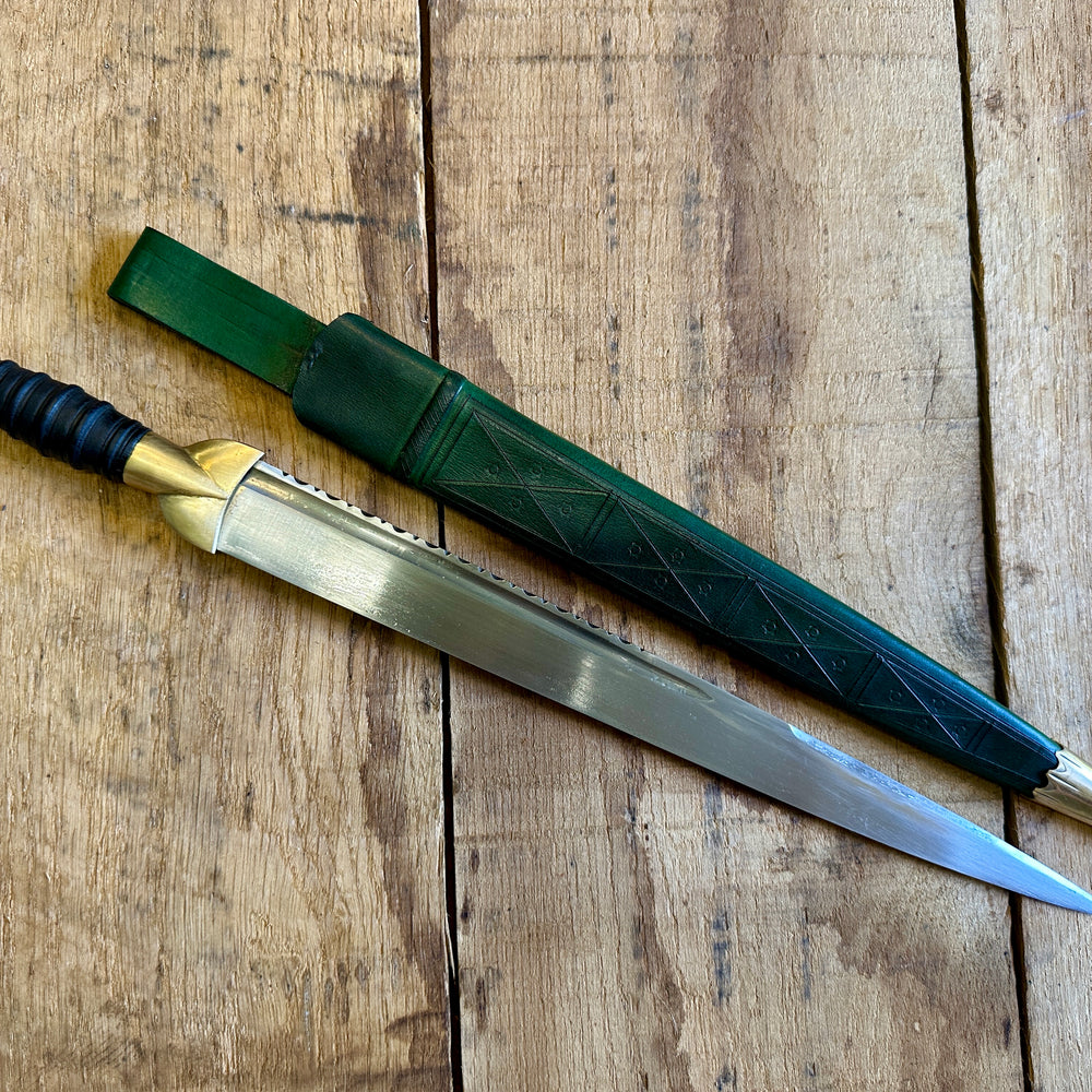 
                  
                    18thC long brass and wood dirk. With green scabbard. 
                  
                