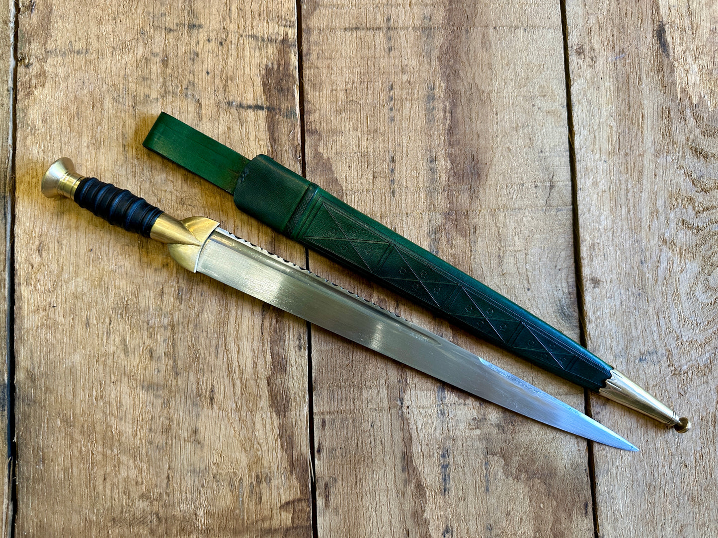 
                  
                    18thC long brass and wood dirk. With green scabbard. 
                  
                