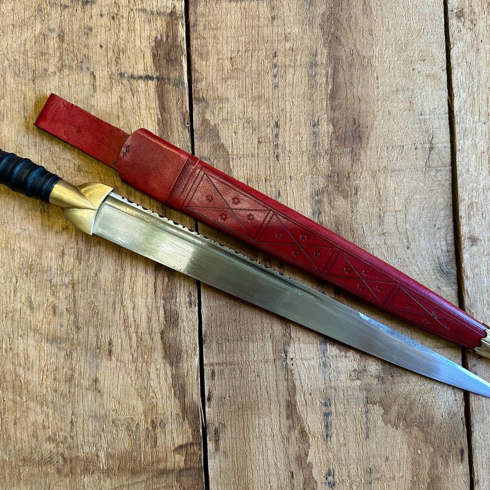 
                  
                    18thC long brass and wood dirk. With red scabbard. 
                  
                