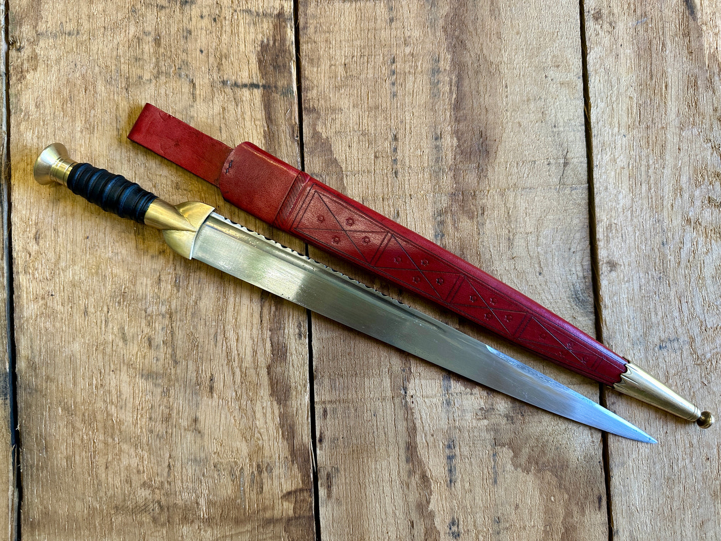 
                  
                    18thC long brass and wood dirk. With red scabbard. 
                  
                