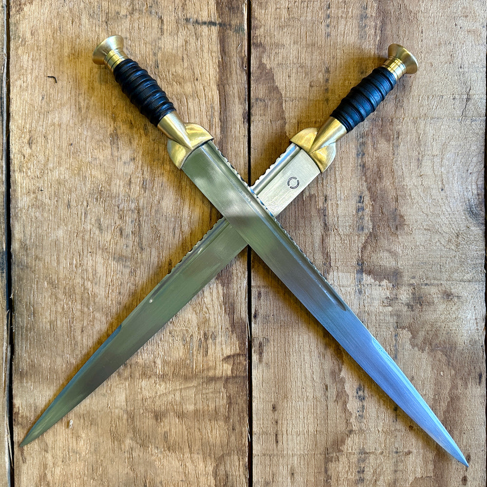 
                  
                    18thC long brass and wood dirk. Two knives crossed.
                  
                