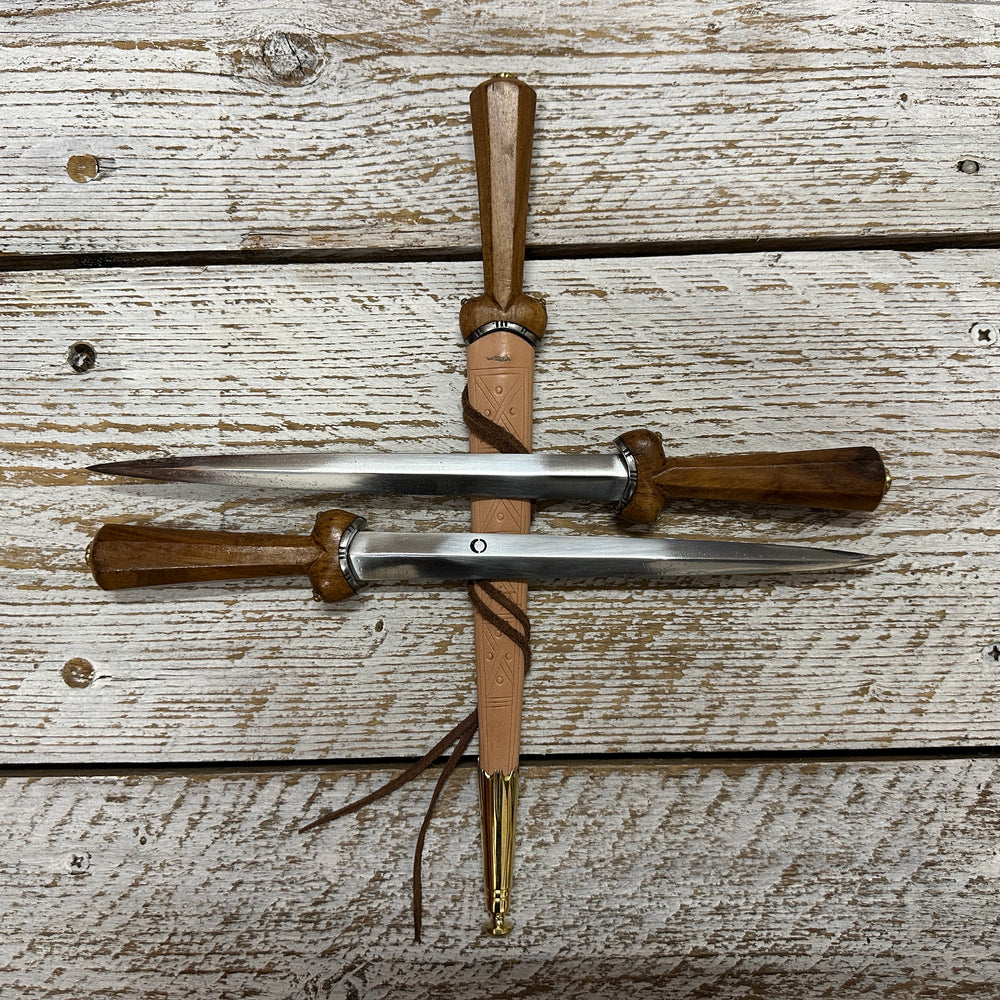 Two Dudgeon Daggers resting on another one in a natural scabbard