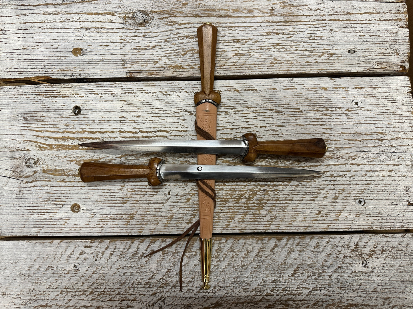 Two Dudgeon Daggers resting on another one in a natural scabbard