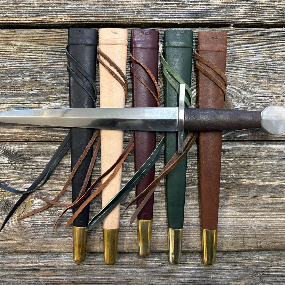12-17thC Quillon Dagger resting on black, natural, red, green and brown scabbards in a row.