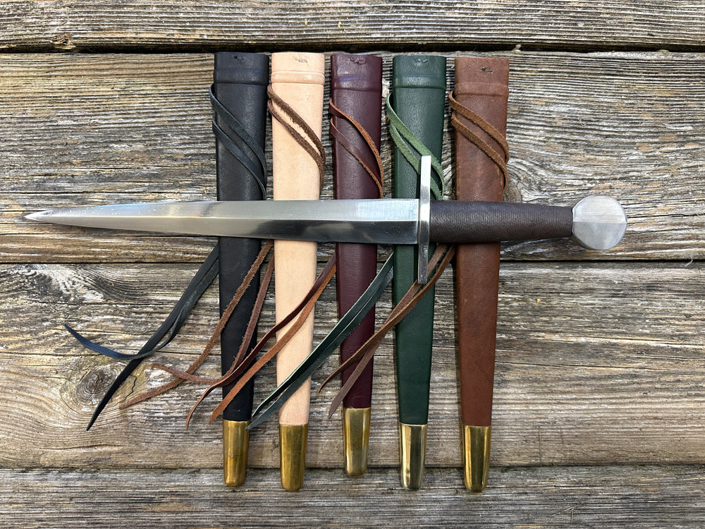12-17thC Quillon Dagger resting on black, natural, red, green and brown scabbards in a row.