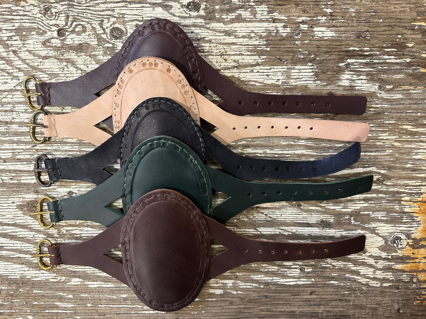 Oval archery bracers in a row descending from red, natural, black, green and brown