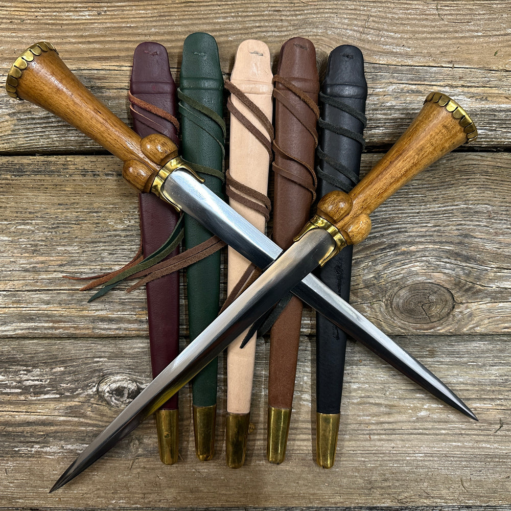 Mid status bollock dagger. Two knives lying on a red, green, natural, brown and black scabbard