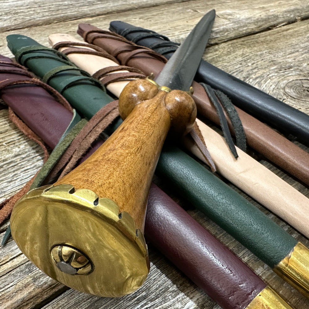 Mid status bollock dagger resting on a bed of scabbards and viewed from the top down