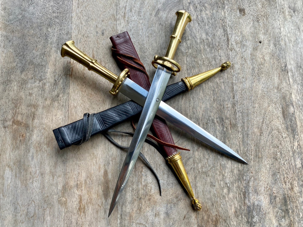 
                  
                    two Tod Cutler S Quillon daggers with a red and black sheath
                  
                