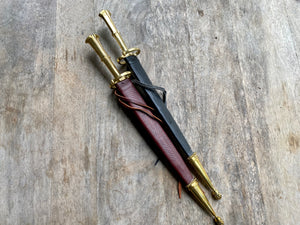 
                  
                    Two S quillon daggers in sheathes, one red and one black
                  
                