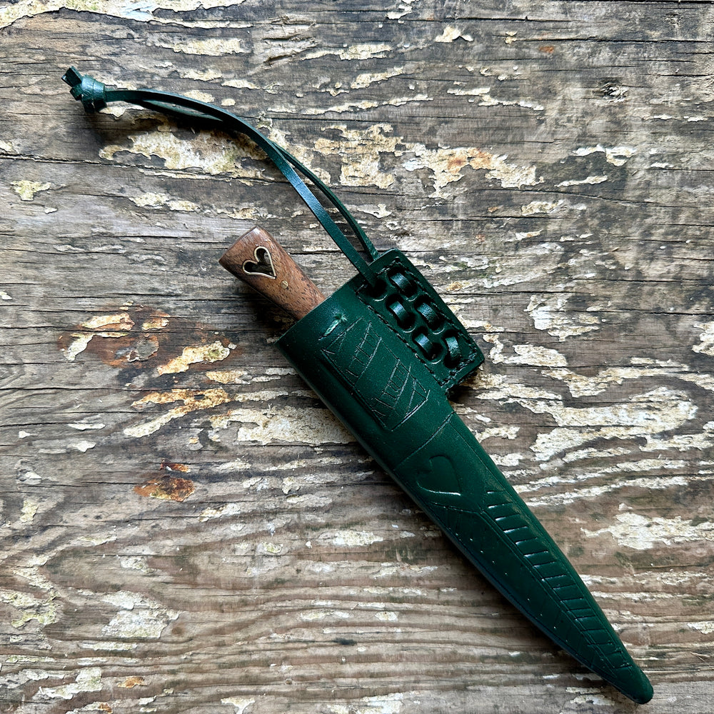 
                  
                    Heart eating knife with a  inside a green sheath
                  
                