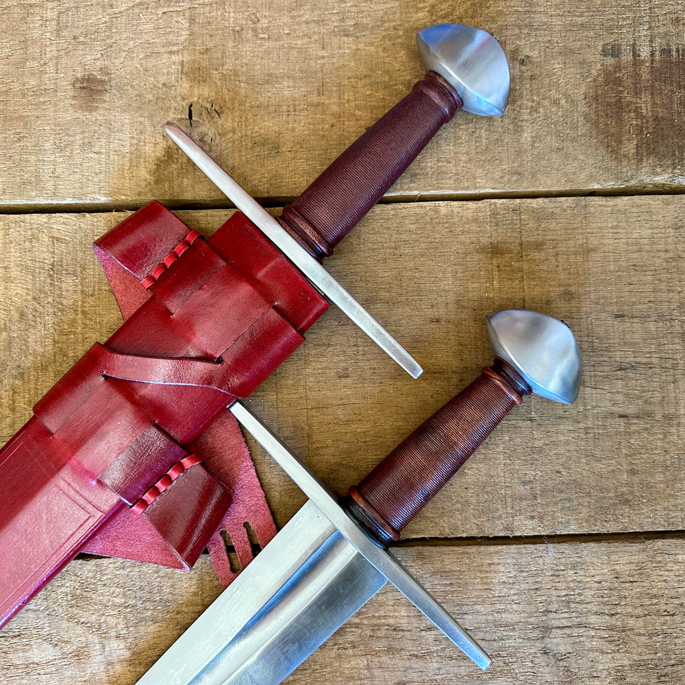 
                  
                    Two Viking Norman Brazil Nut Swords next to each other, one in a red scabbard
                  
                