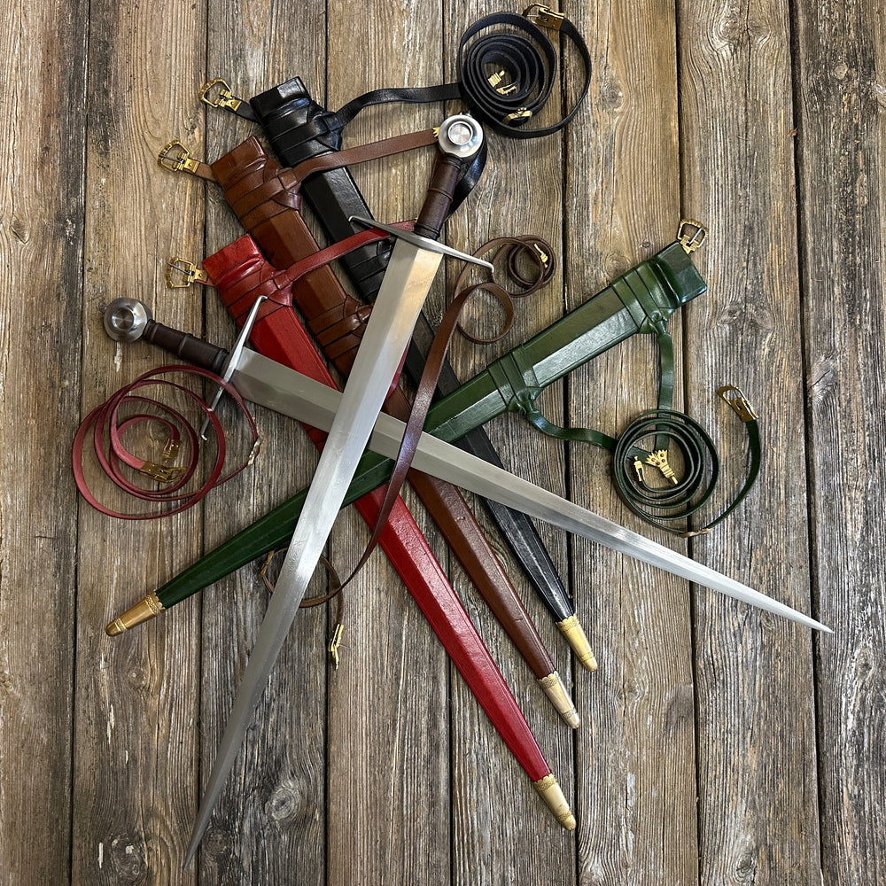 Two Castillon swords resting on red, brown, black and green scabbards with curled belts all around. 