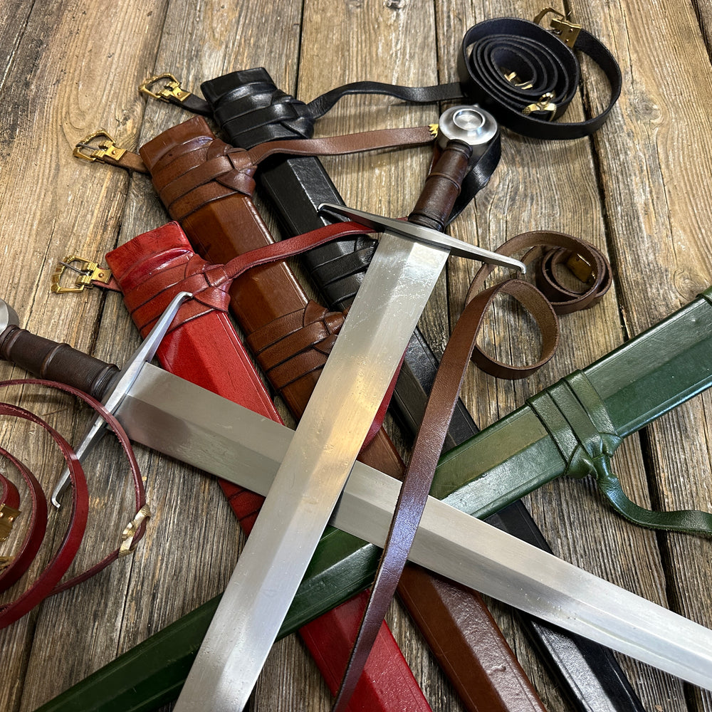 Two Castillon swords resting on red, brown, black and green scabbards with curled belts all around. Zoomed in 