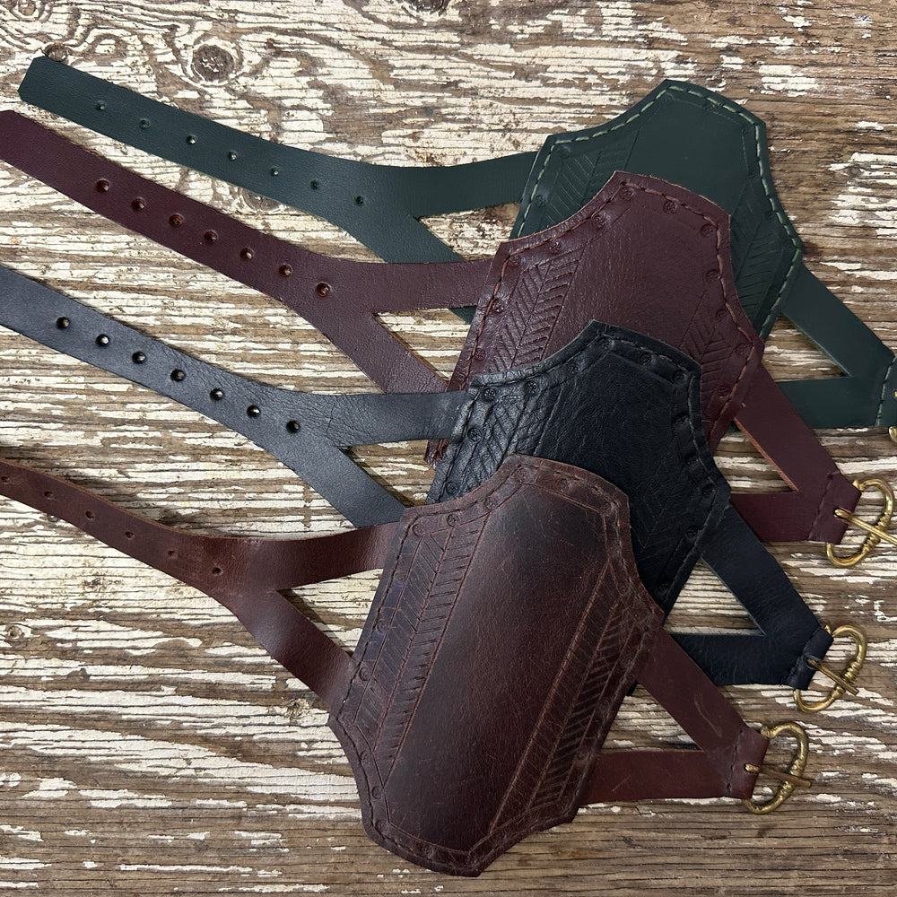 Rectangular archery bracers arranged in descending order from green, red, black and brown