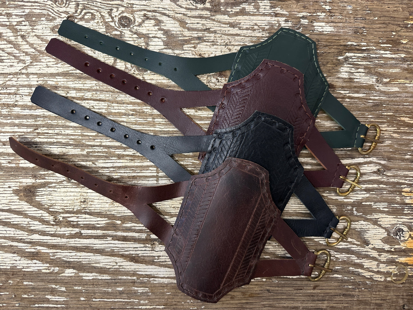 Rectangular archery bracers arranged in descending order from green, red, black and brown
