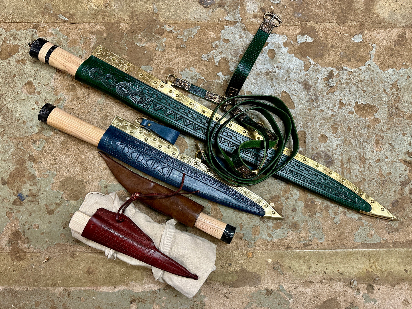 Bundle of Sword Seax, Langseax, Viking everyday carry and viking eating knife in their scabbards with a cotton sword bag rolled up next to them. 